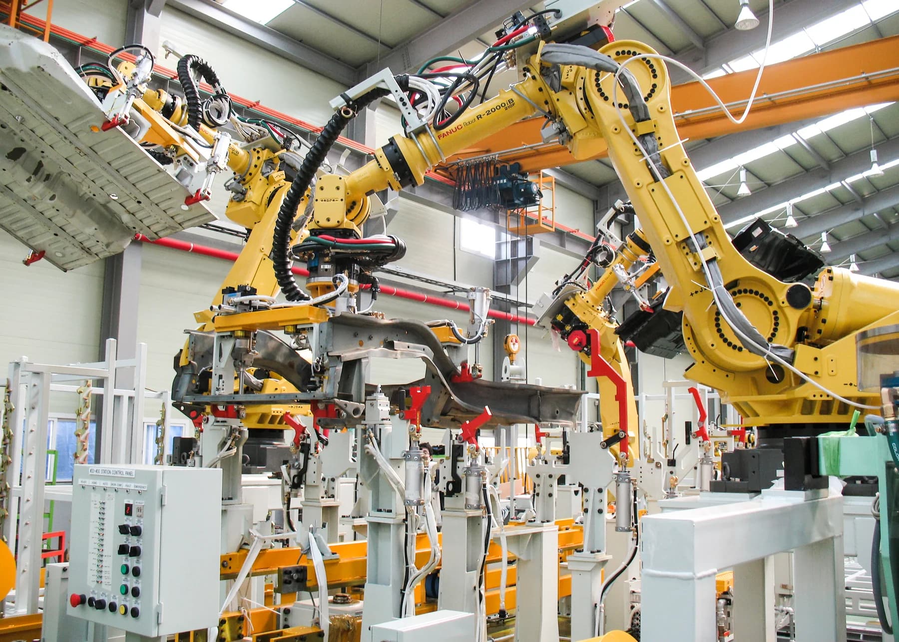 Yellow FANUC R-2000iB industrial robot in a production cell